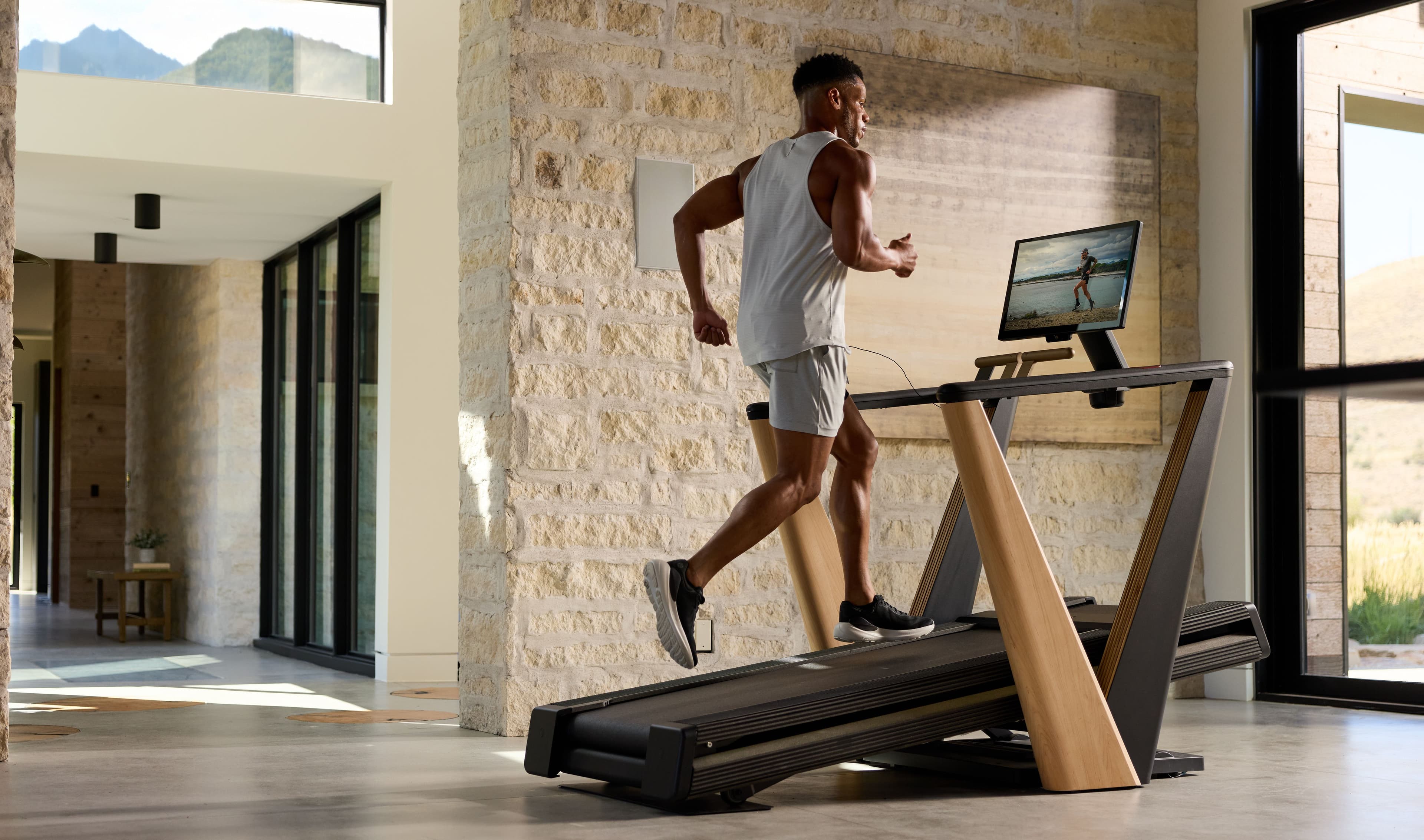 A runner trains on the NordicTrack Ultra 1 treadmill in a light-filled modern home, showcasing the award-winning walnut and bronze design built for living spaces.